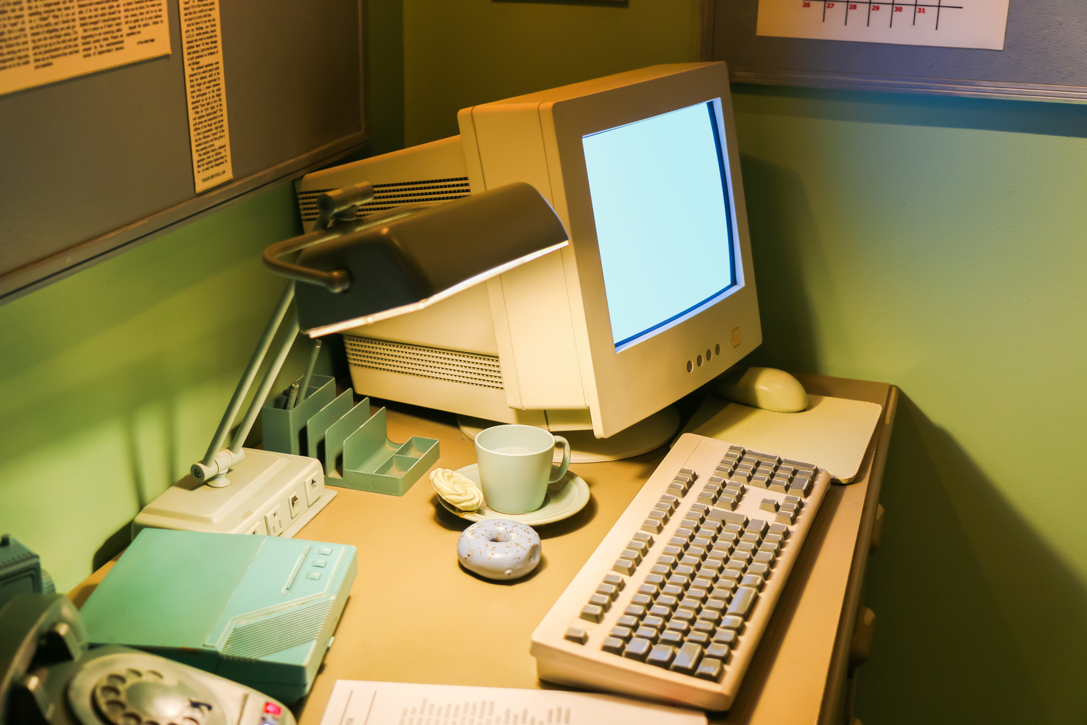 Old 90s computer with keyboard and lit up lamp.