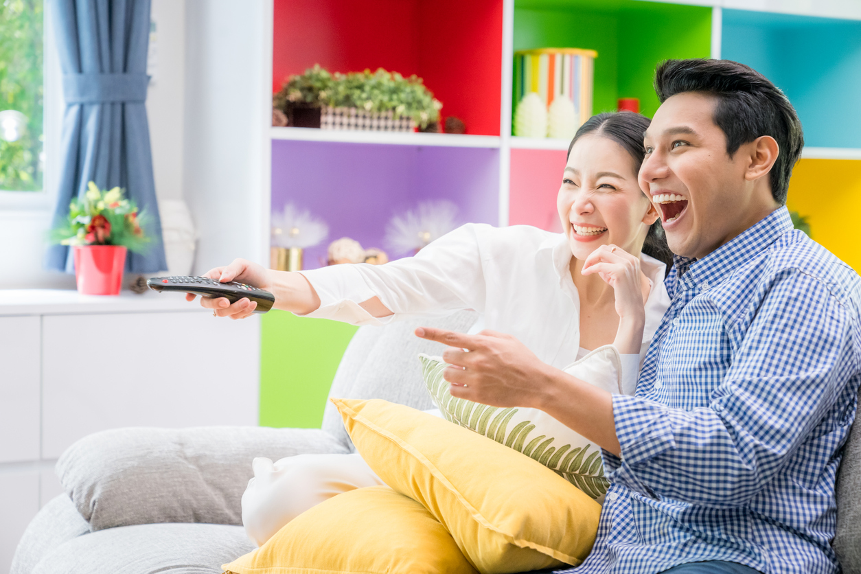 An excited couple happily watching TV.