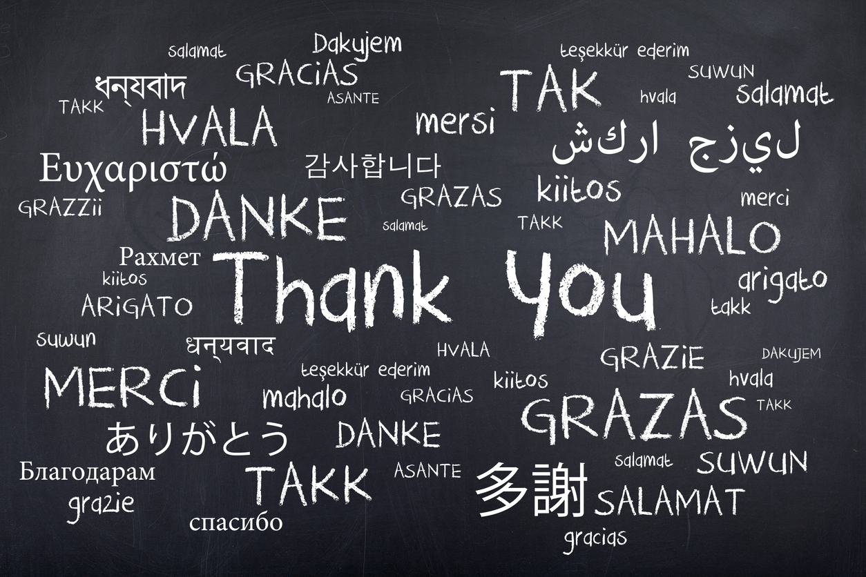 Different translations of thank you handwritten on a black board