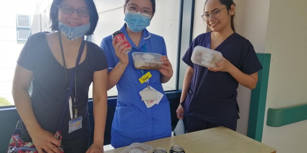 Three nurses happily holding up food from Kabayan Remit