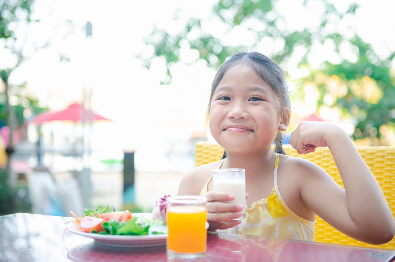 Girl eating healthy food and proudly holding a glass of milk